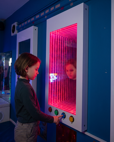 Child exploring the Interactive RGB Infinity Mirror Panel in a sensory room